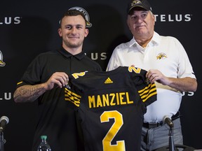 Former NFL quarterback and Heisman Trophy winner Johnny Manziel, left, holds a jersey with Hamilton Tiger-Cats head coach June Jones after announcing that he has signed a two-year contract to play in the CFL for the Tiger-Cats at a press conference in Hamilton, Ont., Saturday, May 19, 2018. THE CANADIAN PRESS/Aaron Lynett ORG XMIT: AJL101