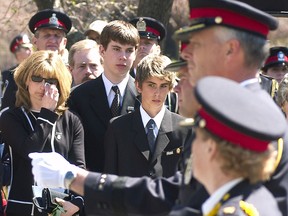 Joanne Kuzmich, wife of South Simcoe Police Constable Alan Kuzmizh, reacts to a parade of police officers from across Ontario at the dedication of an inscription at the Ontario Police Memorial in honour of her husband who was killed in the line of duty last year. Standing with her to her right are her teenage sons, Greg and Bradley.