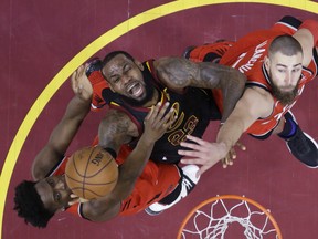 Cleveland Cavaliers' LeBron James (23) goes up for a shot between Toronto Raptors' OG Anunoby, left, and Jonas Valanciunas during the first half of Game 3 of an NBA basketball second-round playoff series Saturday, May 5, 2018, in Cleveland. (AP Photo/Tony Dejak) ORG XMIT: OHRS124