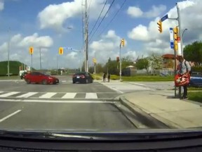 A black car races through a red light at Steeles Ave. and Gihon Spring Dr. on May 15, 2018. (screengrab)