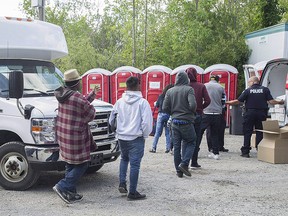 Asylum seekers line up to receive boxed lunches after entering Canada from the U.S. at Roxham Rd. in Hemmingford, Que., in this Aug. 9, 2017 file photo.