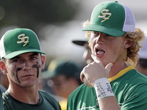 Santa Fe High School baseball player Rome Shubert, right, talks with teammates while wearing the initials of the school shooting victims on his wrist before a baseball game against Kingwood Park High School in Deer Park, Texas, Saturday, May 19, 2018. (AP Photo/David J. Phillip)