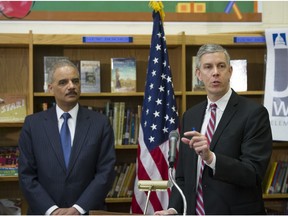 Education Secretary Arne Duncan, right, accompanied by Attorney General Eric Holder, speaks about the importance of universal access to preschool and the need to reduce "unnecessary and unfair school discipline practices and other barriers to equity and opportunity at all levels of education" Friday, March 21, 2014, at J. Ormond Wilson Elementary School in Washington.