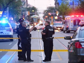 Toronto paramedics transport one of three victims of a brazen daylight shooting on Queen St. West near Peter St. just before 8 p.m. on Saturday.  Victor Biro photo