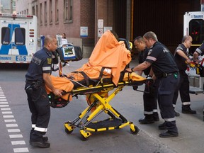 Toronto paramedics transport one of three victims of a brazen daylight shooting on Queen St. West near Peter St. just before 8 p.m. on Saturday. Two victims were rushed to hospital in life-threatening condition. Victor Biro photo