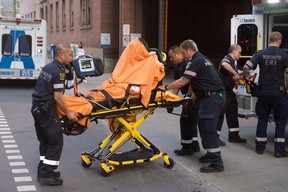 Toronto paramedics transport one of three victims of a brazen daylight shooting on Queen St. West near Peter St. just before 8 p.m. on Saturday. Two victims were rushed to hospital in life-threatening condition. Victor Biro photo