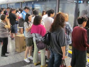 In this undated photo, passengers wait for protective plexiglas barriers to open before boarding subway cars in Hong Kong. (Toronto Sun files)