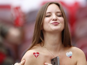 A woman with both the colours of Denmark and Russia painted on her shoulders reacts to the cameras before the start of the group C match between Denmark and France at the 2018 soccer World Cup at the Luzhniki Stadium in Moscow, Russia, Tuesday, June 26, 2018. (AP Photo/Matthias Schrader)