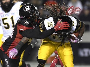 Hamilton Tiger-Cats running back Alex Green (15) gets tackled by Ottawa Redblacks defensive lineman Jonathan Newsome (43) in Ottawa on Friday, Oct. 27, 2017. (THE CANADIAN PRESS/Justin Tang)