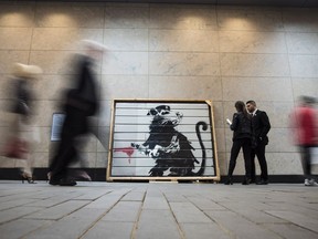 People make their way past the "Saving Banksy" exhibit in Yorkville Village in Toronto on Wednesday, June 6, 2018.