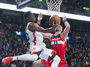 Toronto Raptors' DeMar DeRozan, left, drives to the basket as Washington Wizards' Marcin Gortat defends during first quarter NBA pre-season basketball action in Montreal, Friday, October 23, 2015. THE CANADIAN PRESS/Graham Hughes