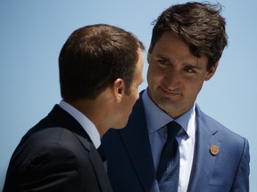 Prime Minister Justin Trudeau speaks with French President Emmanuel Macron during a G-7 summit welcome ceremony, Friday, June 8, 2018, in Charlevoix, Que. (AP Photo/Evan Vucci)