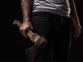 A man holds an ax in his hands against on black background. Criminal