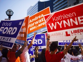 People hold signs ahead of the Ontario Elections Leaders debate at the CBC building in Toronto, Sunday May 27, 2018. (THE CANADIAN PRESS/Mark Blinch)