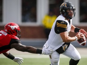 Hamilton Tiger-Cats quarterback Jeremiah Masoli, right, escapes from Calgary Stampeders' Micah Johnson during first half CFL football action in Calgary, Saturday, June 16, 2018.THE CANADIAN PRESS/Jeff McIntosh