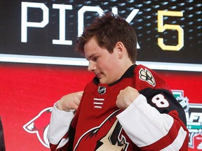Barrett Hayton, of Canada, puts on a jersey after being selected by the Phoenix Coyotes during the NHL hockey draft in Dallas, Friday, June 22, 2018.
