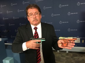Toronto Police Senior Firearms Officer Bruce Finn holds up some of the more colourful handguns that were seized in Project Patton, which targeted the Five Point Generalz street gang, at Toronto Police Headquarters on Friday, June 22 2018.
