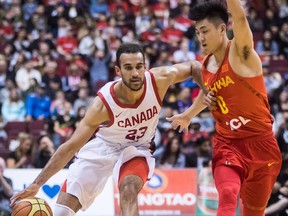 Canada's Phil Scrubb, left, moves the ball past China's Shiyan Gao during second half Pacific Rim Basketball Classic action in Vancouver on June 22, 2018.