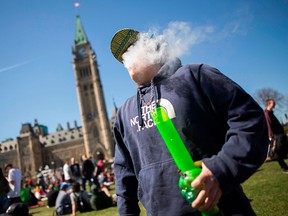In this file photo taken on April 20, 2016 a man smokes marijuana as others gather to celebrate National Marijuana Day on Parliament Hill in Ottawa on April 20, 2016.