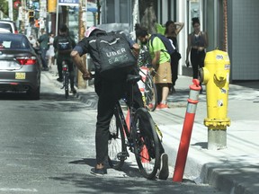 A cyclist didn't realize until the last moment that the pavement was broken up even though orange traffic pylons were there showing a breakage along Queen St. W. just east of Spadina Ave. in Toronto on Tuesday June 19, 2018. (Jack Boland/Toronto Sun/Postmedia Network)