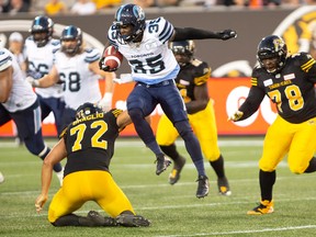 Toronto Argonauts running back Brandon Burks leaps over Hamilton Tiger-Cats defensive end Roman Braglio during CFL action in Hamilton on June 1, 2018