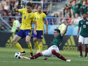 Mexico's Hector Herrera, center, and Sweden's Albin Ekdal, left, challenge for the ball during the group F match between Mexico and Sweden, at the 2018 soccer World Cup in the Yekaterinburg Arena in Yekaterinburg, Russia, Wednesday, June 27, 2018.