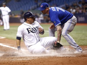 Wilson Ramos #of the Tampa Bay Rays slides home safely ahead of pitcher John Axford of the Toronto Blue Jays to score off of a throwing error by Axford during the seventh inning of a game on June 11, 2018