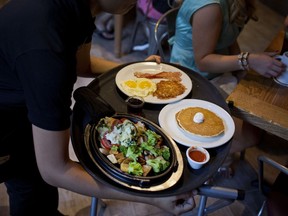A waitress delivers a tray of food to customers at a Denny's restaurant in New York on Sept. 6, 2014. MUST CREDIT: Bloomberg photo by Victor J. Blue.