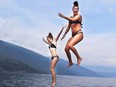Lauren Hunt, left, and Grace MacNaull ham it up mid-air while jumping off the top deck of the Amity II houseboat.