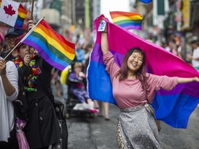 A woman dances with a bisexual pride flag during the Dyke March 2018 along Yonge St. in downtown Toronto, Ont. on Saturday June 23, 2018. Ernest Doroszuk/Toronto Sun/Postmedia