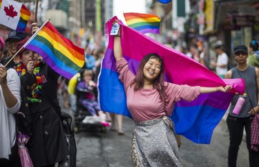 A woman dances with a bisexual pride flag during the Dyke March 2018 along Yonge St. in downtown Toronto, Ont. on Saturday June 23, 2018. Ernest Doroszuk/Toronto Sun/Postmedia