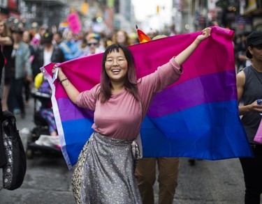 A woman dances with a bisexual pride flag during the Dyke March 2018 along Yonge St. in downtown Toronto, Ont.  on Saturday June 23, 2018. Ernest Doroszuk/Toronto Sun/Postmedia