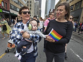 Patricia Homer looks on as Alison Aston holds their 4 month old baby, Rosemary, in the Dyke March 2018 along Yonge St. in downtown Toronto, Ont.  on Saturday June 23, 2018. Ernest Doroszuk/Toronto Sun/Postmedia