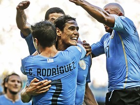 Uruguay's Edinson Cavani, center, celebrates with teammates after kicking a penalty shot to score his side's first goal during the group D World Cup soccer match between Uruguay and Costa Rica at the Arena Castelao in Fortaleza, Brazil, Saturday, June 14, 2014.  (AP Photo/Natacha Pisarenko)