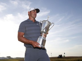Brooks Koepka holds up the Golf Champion Trophy after winning the U.S. Open in Southampton, N.Y., Sunday, June 17, 2018.
