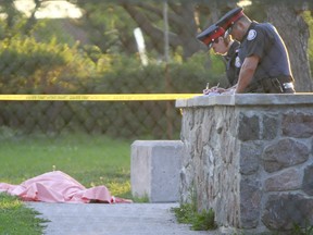 Police take notes after the body of a boy, believed to be about 16, was discovered on a basketball court along Jane St., north of Finch Ave., in July 2007.