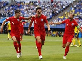 England's Harry Maguire (centre) celebrates with his teammates after scoring his side's opening goal against Sweden on Saturday. (AP PHOTO)