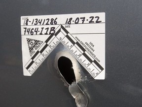 Police foresnic markers surround a bullet hole in the door of a car parked along Danforth Ave. on Monday. (Craig Robertson/Toronto Sun)