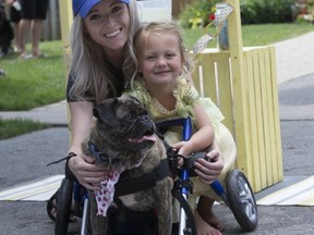 Emma, 4, who sold lemonade to raise money for therapy and a wheelchair for her dog Copper after he broke his back, is seen here with her beloved pooch and her mom Shannin on Friday, July 13, 2018. (Stan Behal/Toronto Sun/Postmedia Network)