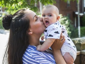 Sammy Barcelos, with one her kids, Reese, on the balcony balcony of their home, near Queen St. W. and Spadina Ave. (ERNEST DOROSZUK, Toronto Sun)