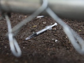 A discarded needle, with blood in it, sits just behind a fence at the Victoria St. safe injection site. (JACK BOLAND, Toronto Sun)