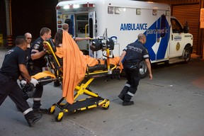 Paramedics attend to a woman shot during a daylight shooting along Queen St. W. near Peter St. on Saturday, June 30 2018. (Victor Biro photo)