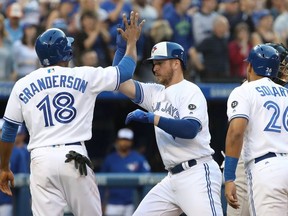 Justin Smoak #14 of the Toronto Blue Jays is congratulated by Curtis Granderson #18 and Yangervis Solarte #26 after hitting a three-run home run in the second inning during MLB game action against the New York Yankees at Rogers Centre on July 6, 2018 in Toronto, Canada.