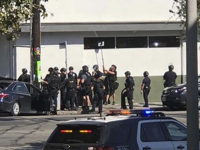 In this photo provided by Christian Dunlop, police officers use a mirror to see inside a Trader Joe's store in the Silver Lake neighborhood of Los Angeles on Saturday, July 21, 2018. Police believe a man involved in the standoff with officers shot his grandmother and girlfriend before firing at officers during a pursuit, then crashing outside the supermarket and running inside the store.