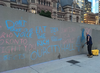 A city worker scrubbs angry messages scrawled on a wall at City Hall after Ontario Premier Doug Ford announced plans to cut City Council from 47 to 25 councillors on Friday, July 17, 2018. (Joe Warmington/Toronto Sun/Postmedia Network)