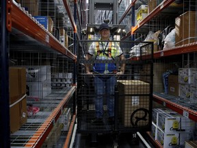 An Amazon employee works at the new Amazon warehouse in Boves, northern France, Tuesday, Oct. 3, 2017. THE CANADIAN PRESS/Yoan Valat/Pool Photo via AP