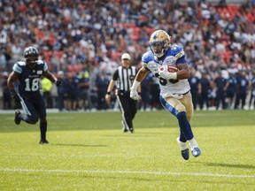 Toronto Argonauts Eric Striker, left, looks on as Winnipeg Blue Bombers' Andrew Harris scores a touchdown during first half CFL football action in Toronto on Saturday, July 21, 2018. THE CANADIAN PRESS/Mark Blinch