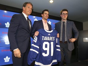 Maple Leafs president Brendan Shannon (left) and general manager Kyle Dubas (right) pose with John Tavares, who signed a seven-year, $77 million contract on the first day of NHL free agency in Toronto on Sunday, July 1, 2018.