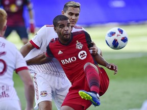 Toronto FC forward Jordan Hamilton (front) protects the ball from New York Red Bulls midfielder Aaron Long during first half MLS action in Toronto on Sunday, July 1, 2018.