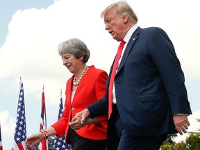 U.S. President Donald Trump and British Prime Minister Theresa May hold hands at the conclusion of their joint news conference at Chequers, in Buckinghamshire, England, Friday, July 13, 2018.